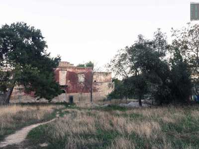...mentre sulla sinistra si apre un grande campo abbandonato con un sentiero che conduce direttamente a una casa rossa...